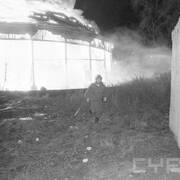 strażak w ubraniu bojowym, w tle płonący budynek