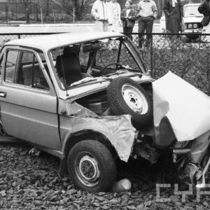 zniszczony samochód fiat 126p na torowisku tramwajowym, w tle przyglądający się gapie
