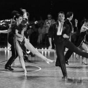 grupa młodych ludzi w strojach balowych tańczących na parkiecie