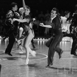 grupa młodych ludzi w strojach balowych tańczących na parkiecie