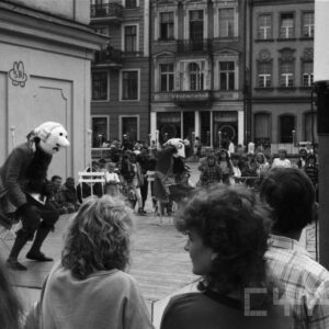 aktorzy w przebraniach występujący przed grupą ludzi na scenie ustawionej na tle zabytkowych kamienic
