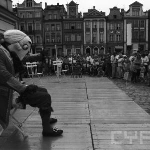 aktorzy w przebraniach występujący przed grupą ludzi na scenie ustawionej na tle zabytkowych kamienic