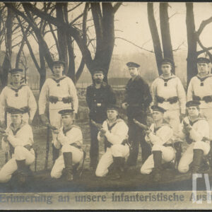 grupa młodych mężczyzn w mundurach, w rękach trzymają karabiny, część stoi, część kuca na tle drzew; na dole podpis: Zur Erinnerung na unsere infanteristische Ausbildung
