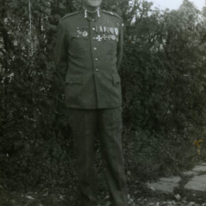 Mężczyzna w mundurze powstańczym stojący na tle zarośli