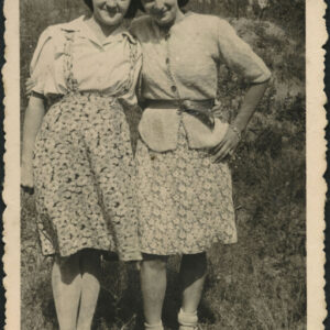 dwie kobiety, przytulające się do siebie stoją na trawie