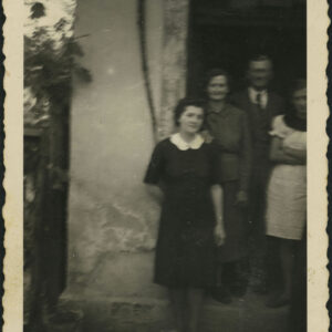 trzy kobiety i mężczyzna stoją w wejściu do budynku murowanego