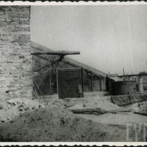 z lewej fragment ceglanej, nieotynkowanej ściany, przy niej szklarnia ze skośnym dachem