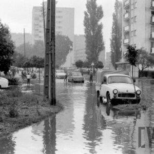 samochody na zalanej wodą ulicy pośród bloków