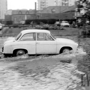 samochód na zalanej wodą ulicy pośród bloków