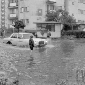 samochód na zalanej wodą ulicy pośród bloków