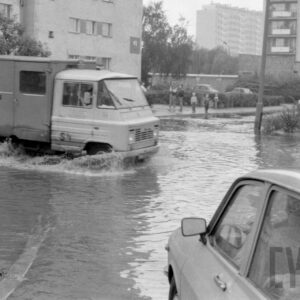 samochody na zalanej wodą ulicy pośród bloków