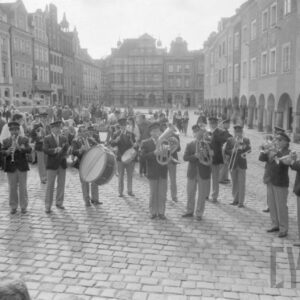 grupa mężczyzn grająca na różnych instrumentach na tle kamienic