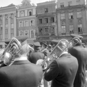 grupa mężczyzn grająca na różnych instrumentach na tle kamienic