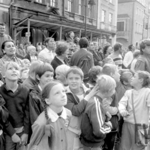 grupa dzieci i dorosłych na tle kamienic