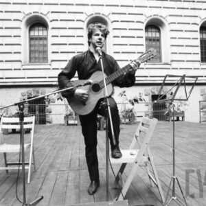 młody mężczyzna grający na gitarze na tle zamku