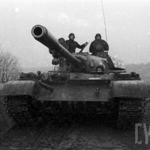 żołnierze siedzący na czołgu na poligonie