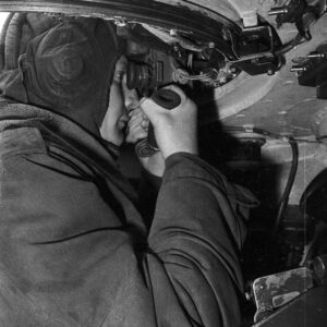 żołnierz patrzący w wizjer (peryskop?) wewnątrz czołgu na poligonie