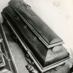 drewniana trumna z krzyżem na wieku na podłodze krypty