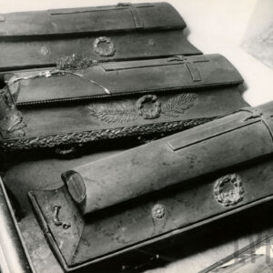 ozdobne, drewniane trumny z krzyżami na wiekach, na jednej wiązanka kwiatów