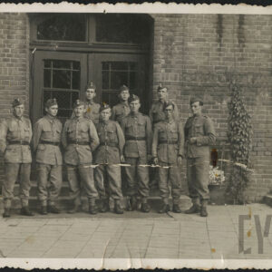 grupa mężczyzn w mundurach wojskowych na tle ceglanego budynku z drewnianymi drzwiami