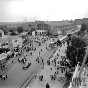 ulica z torami kolejowymi na terenie wystawy, na torach wagony kolejowe, dookoła hale wystawowe, spacerujący ludzie