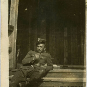 młody mężczyzna w mundurze wojskowym siedzący na drewnianych schodach