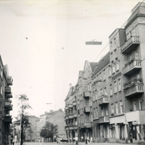 asfaltowa ulica, wzdłuż chodników po obu jej stronach kilkukondygnacyjne kamienice