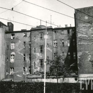 trzypiętrowa kamienica z odrapanym tynkiem na fasadzie