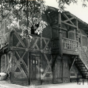 dwukondygnacyjny dom o konstrukcji szkieletowej, drewnianej z drewnianymi schodami prowadzącymi na pierwsze piętro