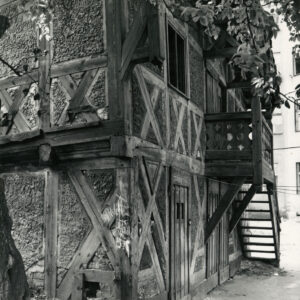 dwukondygnacyjny dom o konstrukcji szkieletowej, drewnianej z drewnianymi schodami prowadzącymi na pierwsze piętro