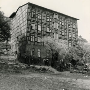 trzypiętrowy budynek o konstrukcji szkieletowej, drewnianej, wypełnionej cegłami, stoi na skarpie