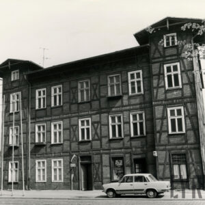 dom dwupiętrowy drewniano-ceglany, przed nim zaparkowany samochód osobowy