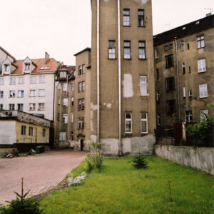 kilkupiętrowa kamienica, przed budynkiem, zielony trawnik