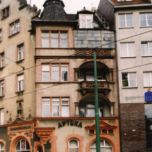 fragment elewacji z dwoma balkonami, na parterze napis nad oknem „apteka”