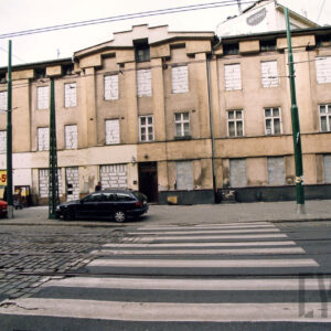 dwupiętrowa kamienica, z częściowo zamurowanymi oknami, na pierwszym planie przejście dla pieszych