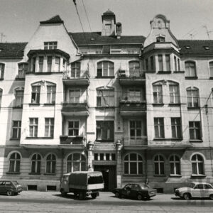 trzypiętrowa kamienica z poddaszem, przed nią zaparkowane samochody