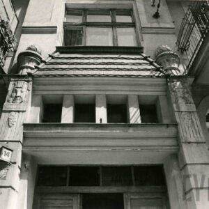 górny fragment drewnianych drzwi, po bokach dwa zdobione pilastry, wszystko zwieńczone daszkiem pokrytym dachówką