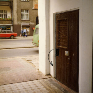 w ścianie drewniane drzwi, w głębi fragment ulicy