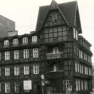 dwupiętrowy dom drewniano-ceglany z użytkowym poddaszem, narożnik z dodatkową kondygnacją, nakrytą stromym dwuspadowym dachem