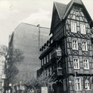 dwupiętrowy dom drewniano-ceglany z użytkowym poddaszem, narożnik z dodatkową kondygnacją, nakrytą stromym dwuspadowym dachem