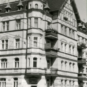 narożnik trzypiętrowej kamienicy z użytkowym poddaszem, elewacja zwieńczona ozdobnym szczytem