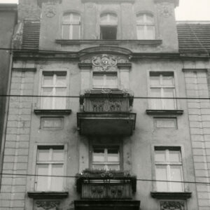 fragment ściany frontowej kamienicy z oknami i balkonami oraz trójkątnym szczytem