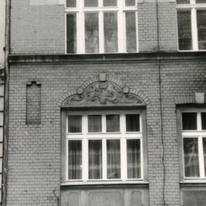 fragment elewacji z dwoma oknami i zdobieniami nad nimi