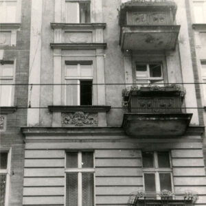 fragment ściany frontowej kamienicy z oknami i balkonami