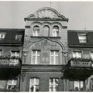 fragment ostatniego piętra kamienicy z mieszkalnym poddaszem zakończony zdobionym szczytem, po bokach balkony