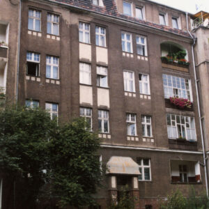 czteropiętrowa kamienica, przed nią z lewej drzewo, przy ulicy zaparkowane samochody