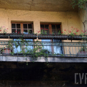 dwa okna balkonowe, balkon z żeliwną balustradą z korytkami i donicami z kwiatami