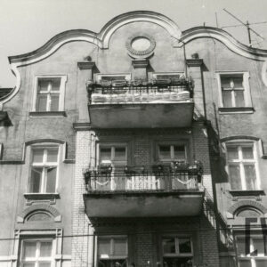 fragment ostatniego piętra kamienicy z mieszkalnym poddaszem zakończony zdobionym szczytem, na środku balkony