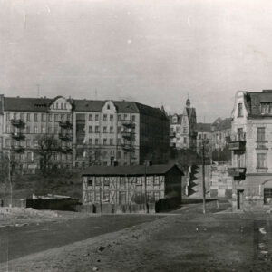 w środku dwukondygnacyjny dom drewniano-ceglany tzw. mur pruski, za nim schody, w głębi kilkupiętrowe kamienice