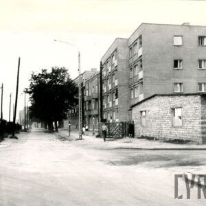 kilkupiętrowe bloki mieszkalne wzdłuż ulicy, z przodu z prawej jednopiętrowy ceglany budynek